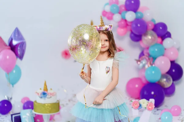 Unicorn Girl holding gold confetti air baloon. Idea for decorating unicorn style birthday party. Unicorn decoration for festival party girl
