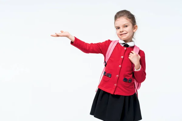 Menina adorável na jaqueta vermelha da escola, vestido preto, mochila apontando para o espaço empy enquanto posando no fundo do estúdio branco. Isolar — Fotografia de Stock
