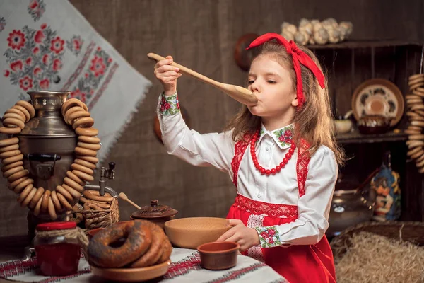 Menina adorável sentada à mesa cheia de comida e grande samovar. Tradicional celebrando Maslenitsa — Fotografia de Stock