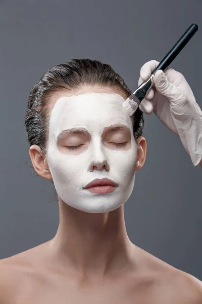 Krásná dívka je aplikována bílá kosmetická maska z černých teček. Izolovat, studio — Stock fotografie