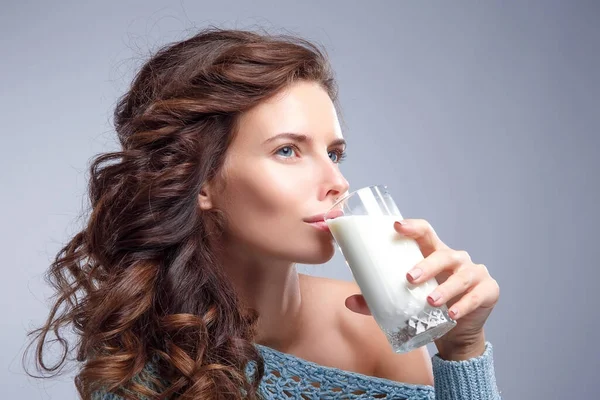 Happy young woman drinking milk over grey background Stock Photo