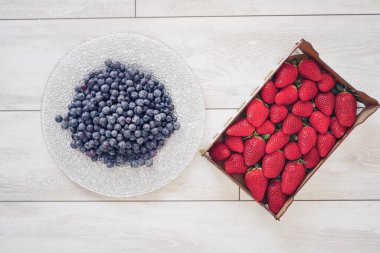 Kutuda çilek ve tabakta yaban mersini.