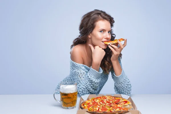 Happy woman with pizza and beer on grey background, space for text