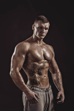 Üstsüz, atletik dövmeli bir erkeğin stüdyo portresi