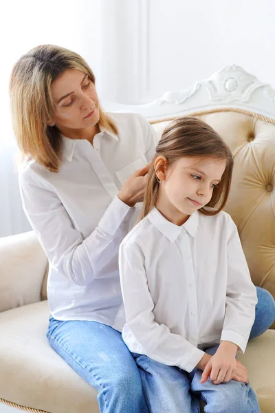 Mom straightens her daughters hair. Parents and children. Family values and relationships of aunts and parents