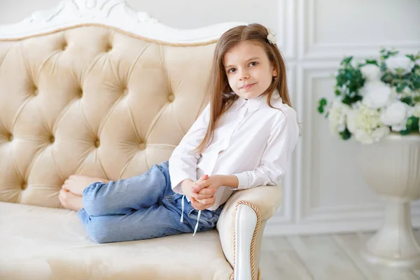 Pequena menina bonito encontra-se no sofá na sala — Fotografia de Stock