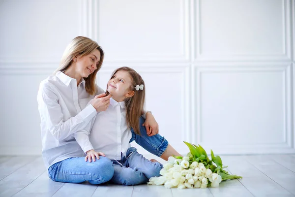 Portrait of little girl loving mother holding her and tulips — Stok Foto