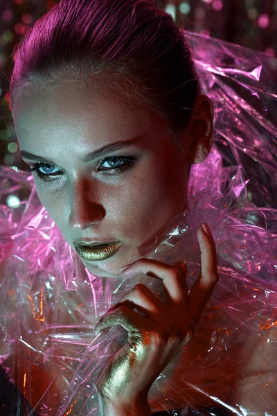 Chica modelo de alta moda en luces de neón brillantes de colores posando en el estudio a través de película transparente. Retrato de hermosa mujer sexy en UV. Diseño de arte maquillaje colorido. Sobre fondo vivo y colorido — Foto de Stock