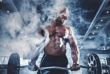 Spor salonunda spor yapan kaslı bir adam, pazularıyla egzersiz yapıyor. Güçlü erkek, çıplak karın kasları var.