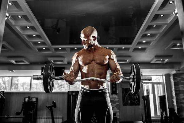 Muskularny mężczyzna ćwiczący na siłowni ćwiczący z hantlami na bicepsach, silny mężczyzna nagi tułów brzucha — Zdjęcie stockowe