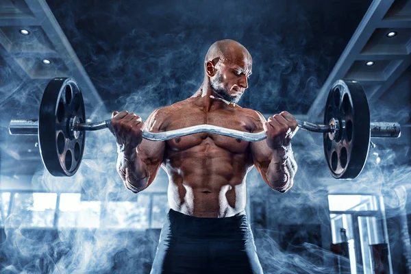 Homem musculoso trabalhando fora no ginásio fazendo exercícios com halteres no bíceps, abdominais fortes tronco nu masculino — Fotografia de Stock
