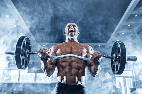 Hombre musculoso ejercitándose en el gimnasio haciendo ejercicios con pesas en bíceps, fuertes abdominales masculinos desnudos del torso —  Fotos de Stock
