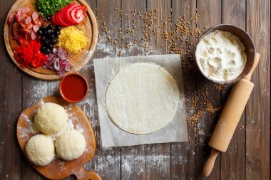 Tahta masadaki malzemeli pizza hamuru.