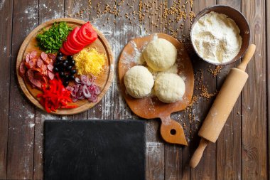 Tahta masadaki malzemeli pizza hamuru.