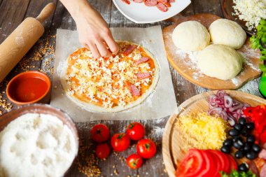 Aşçı mutfakta, pizzanın malzemelerini koyuyor. Pizza konsepti. Gıda üretimi ve teslimatı