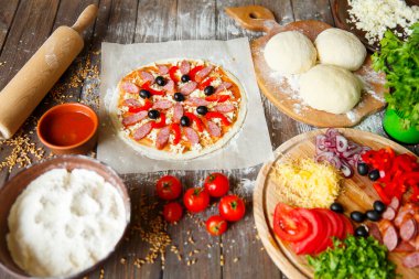 Aşçı mutfakta, pizzanın malzemelerini koyuyor. Pizza konsepti. Gıda üretimi ve teslimatı