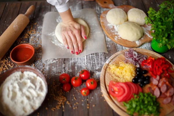 Mulher amassa a massa com as mãos enquanto cozinha — Fotografia de Stock