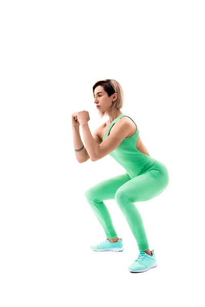 Studio colpo di una donna atletica che fa squat isolato su sfondo bianco — Foto Stock