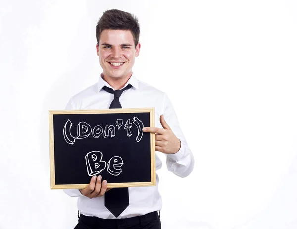 Don't Be - Young smiling businessman holding chalkboard with — Stock Photo, Image