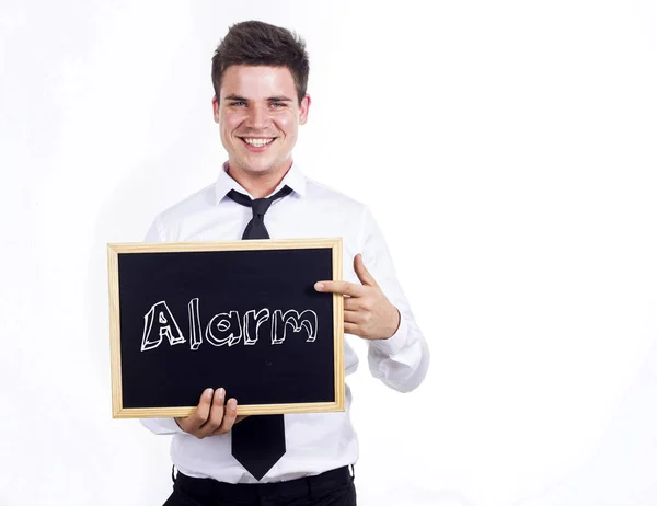 Alarma - Joven hombre de negocios sonriente sosteniendo pizarra con texto —  Fotos de Stock