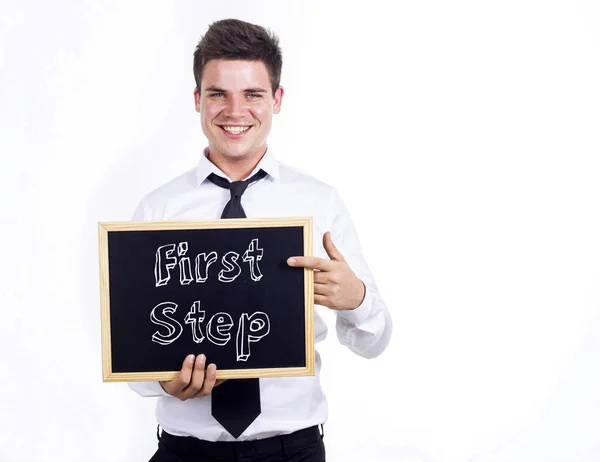 Primeiro passo - Jovem homem de negócios sorrindo segurando quadro com t — Fotografia de Stock