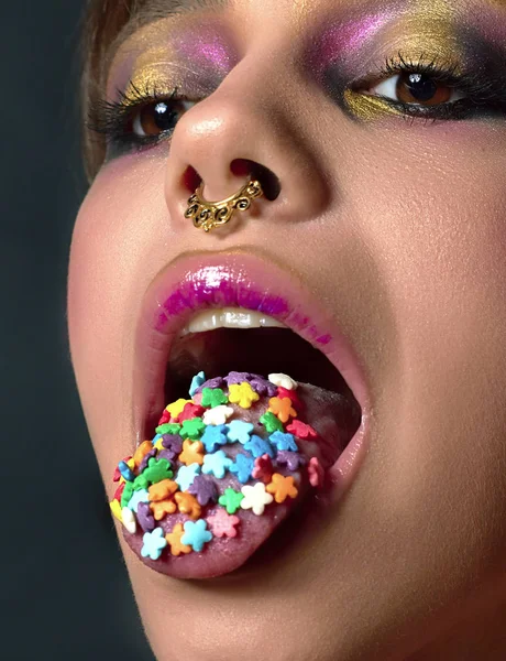 Een charmante meisje met piercing in haar neus. Tussenschot. Mooie vrouw met lichte make-up, roze lippen en snoepjes in mond Stockfoto