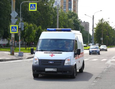Minibus Ambulance on the road ulitsa Dybenko, Saint-Petersburg, Russia July 2017 clipart