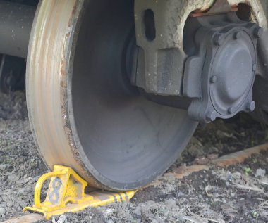 Vagon tekerleği sarı bir fren ayakkabısıyla tıkanmış.