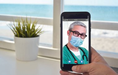 Maskeli doktorla konuşmak için akıllı telefon video çağrısı