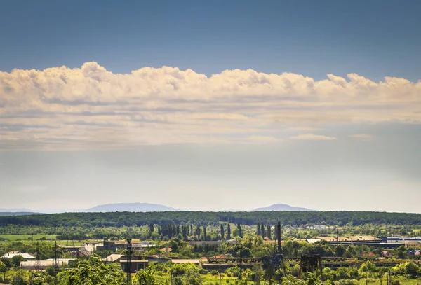 Vackra sommarlandskap med molnig himmel, staden och bergen — Stockfoto