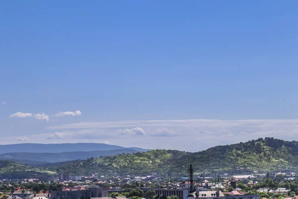 Vackra sommarlandskap med molnig himmel, staden och bergen — Stockfoto