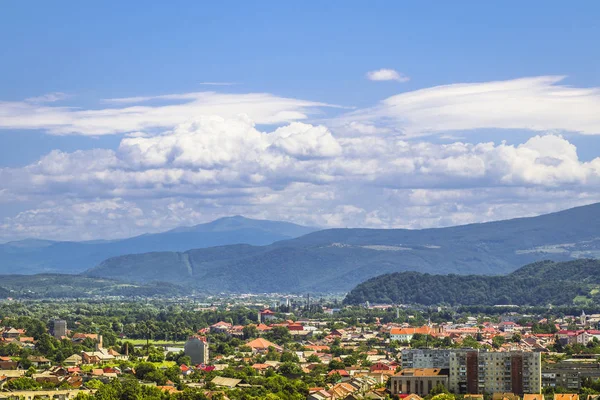 Летний пейзаж с городом, горами и облачным голубым небом — стоковое фото