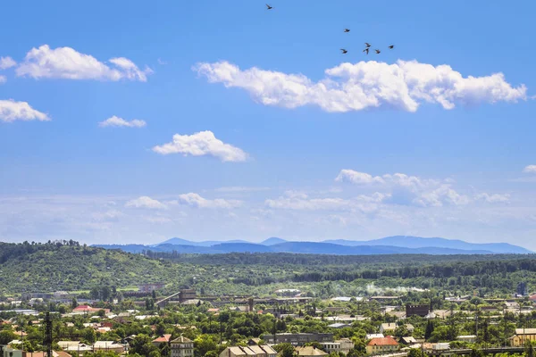 Mooie zomerse landschap met bergen, stad en bewolkte blauwe hemel — Stockfoto