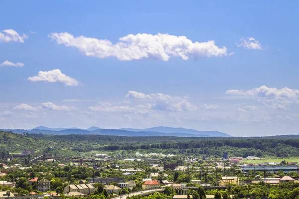 Mooie zomerse landschap met bergen, stad en bewolkte blauwe hemel — Stockfoto