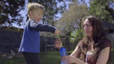 Bir anne ve çocuğu arka bahçedeki kabarcıkları ile oynamak