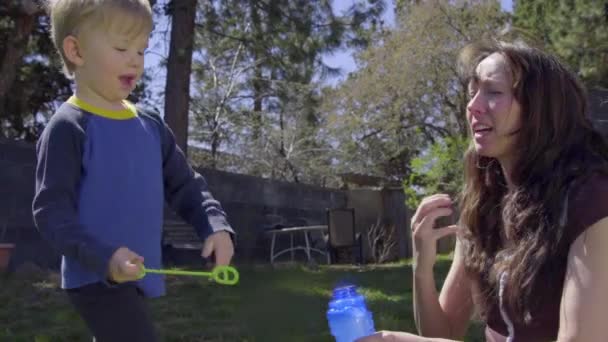 Niño corre hacia la madre y juega con burbujas — Vídeo de stock