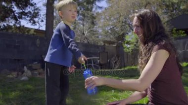 Anne ve oğlu kabarcıklar güneşli bir arka bahçesinde oluşturmak