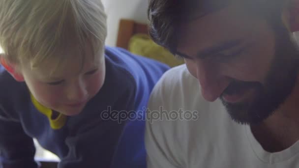 Le jeune garçon est assis sur les genoux de son oncle — Video