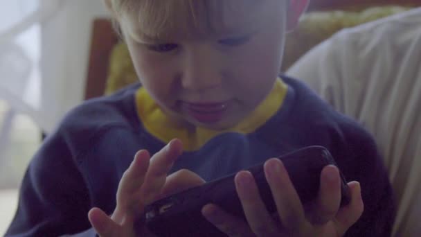 Närbild på liten pojke som spelar på en mobiltelefon — Stockvideo
