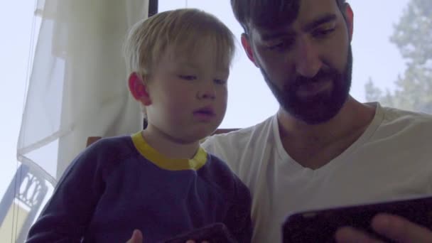 Man laat een spel zien kleine jongen op een mobiele telefoon — Stockvideo