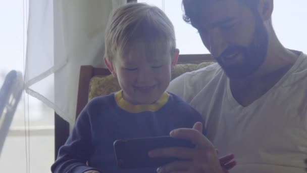 Fechar no bonito pai e filho brincando com o telefone celular — Vídeo de Stock