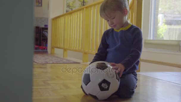 Chico se sienta con pelota de fútbol — Vídeo de stock