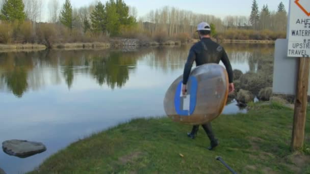 Hombre joven en traje de neopreno con tabla de paddle — Vídeo de stock