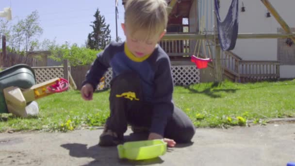 Jongen gespiegeld speelgoed kikker in een emmer — Stockvideo