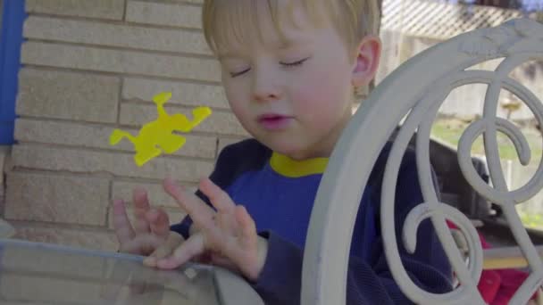 Adorável menino vira sapo brinquedo — Vídeo de Stock