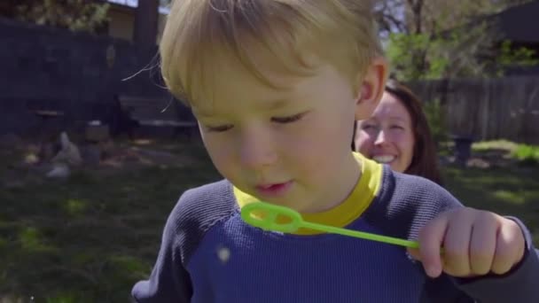 Милий маленький хлопчик дме бульбашки — стокове відео