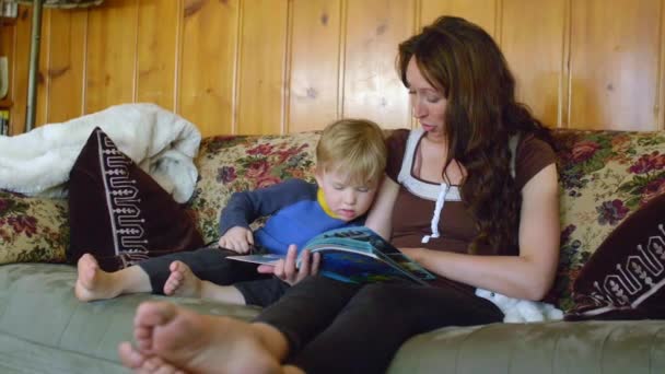 Мальчик смотрит в книгу с матерью — стоковое видео