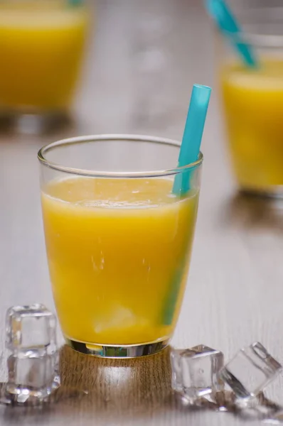 Jus d'orange fraîchement pressé en verre avec paille bleue et glace c — Photo