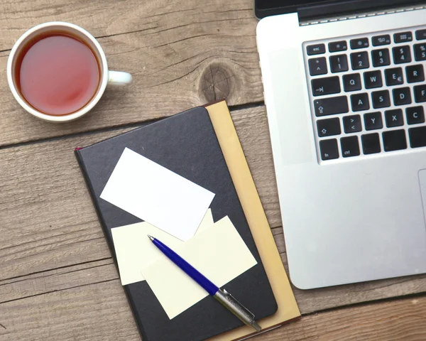 Cartões de visita em branco com caneta, laptop e xícara de chá na mesa de escritório de madeira — Fotografia de Stock