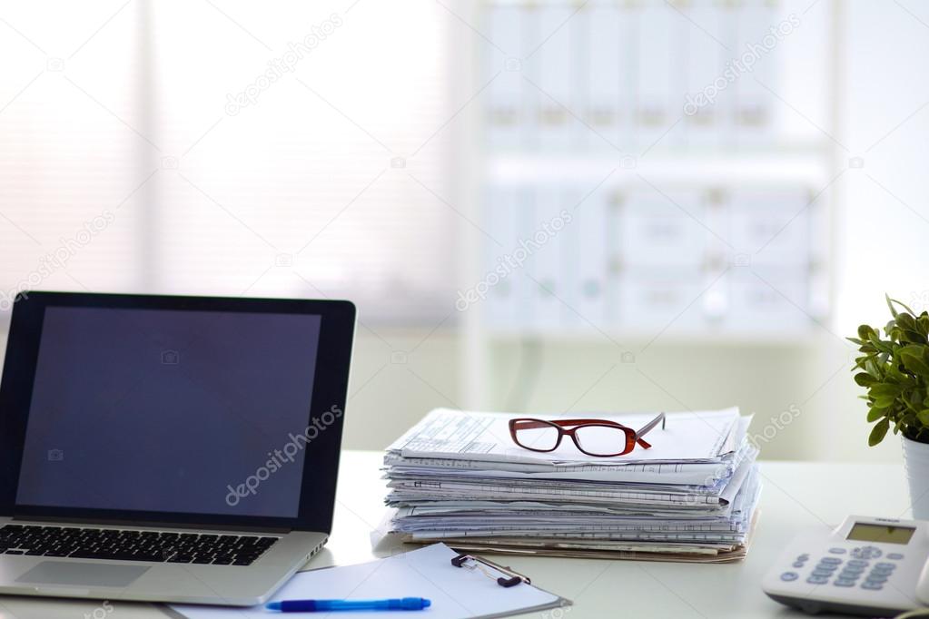 Laptop with stack of folders on table  white background